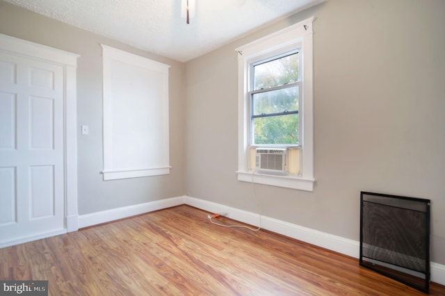 spare room featuring a textured ceiling, light hardwood / wood-style flooring, and cooling unit