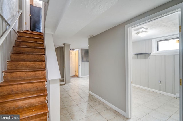 staircase with wood walls, a textured ceiling, and tile patterned flooring