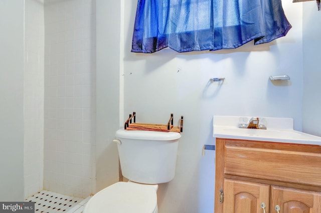 bathroom featuring vanity, toilet, and a tile shower