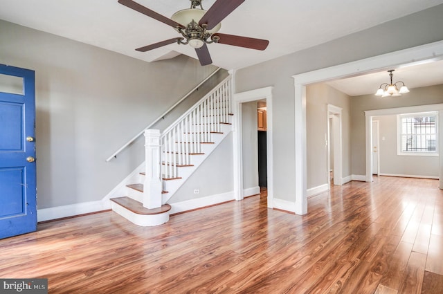 foyer with hardwood / wood-style floors and ceiling fan with notable chandelier