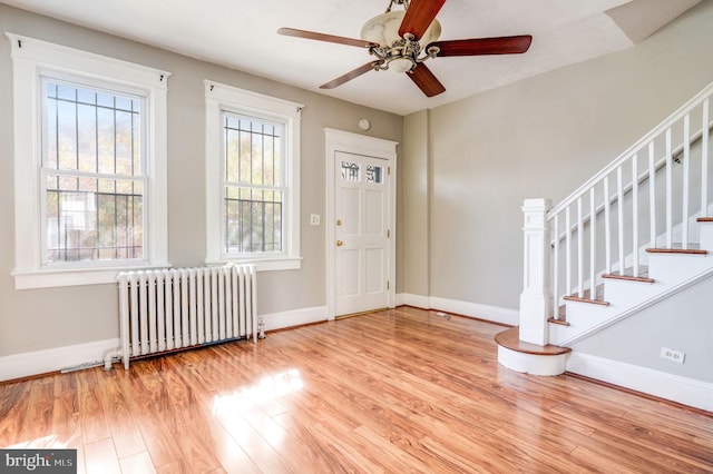 foyer with radiator heating unit, light wood-type flooring, and ceiling fan