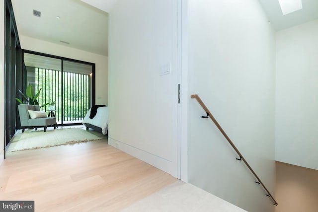 hallway featuring light hardwood / wood-style flooring and a skylight