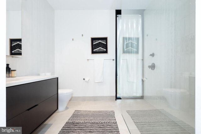 bathroom with toilet, a tile shower, vanity, and tile patterned floors