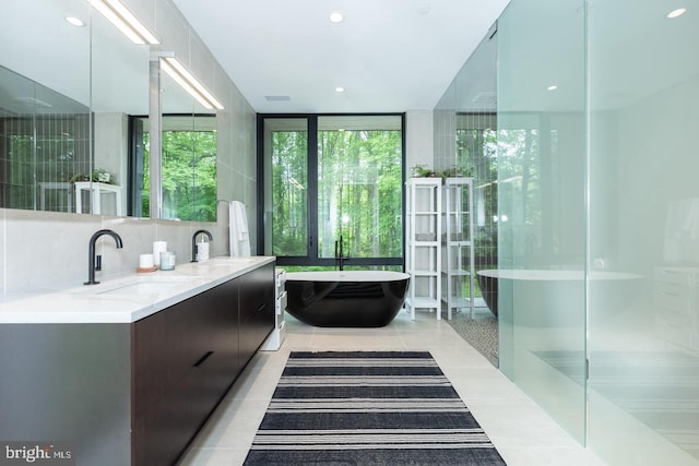 bathroom featuring decorative backsplash, shower with separate bathtub, vanity, a wall of windows, and tile patterned flooring