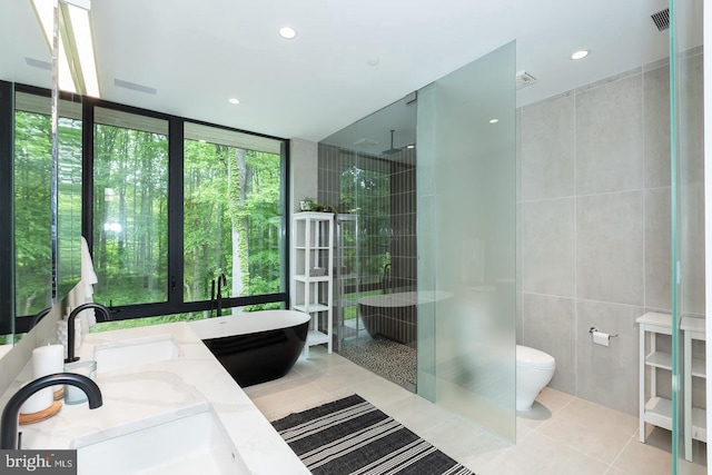 full bathroom featuring plus walk in shower, toilet, tile patterned flooring, vanity, and floor to ceiling windows