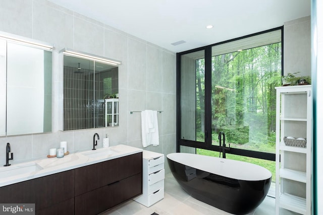 bathroom featuring vanity, tile patterned floors, independent shower and bath, and tile walls