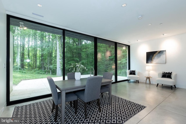 dining area featuring finished concrete floors, expansive windows, and baseboards