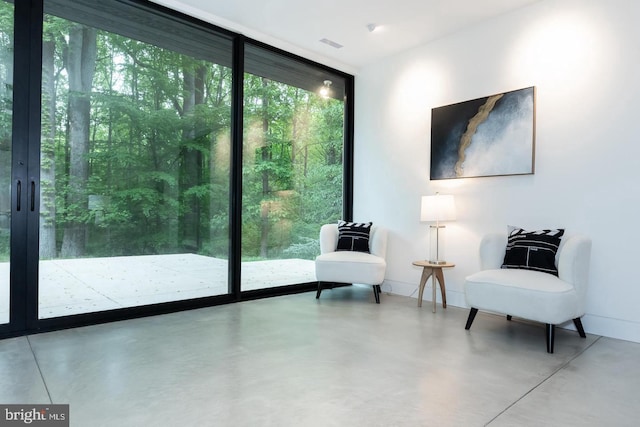 sitting room featuring a wall of windows and concrete flooring