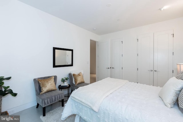 bedroom with concrete floors and baseboards