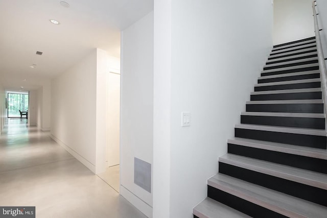 stairs featuring concrete flooring