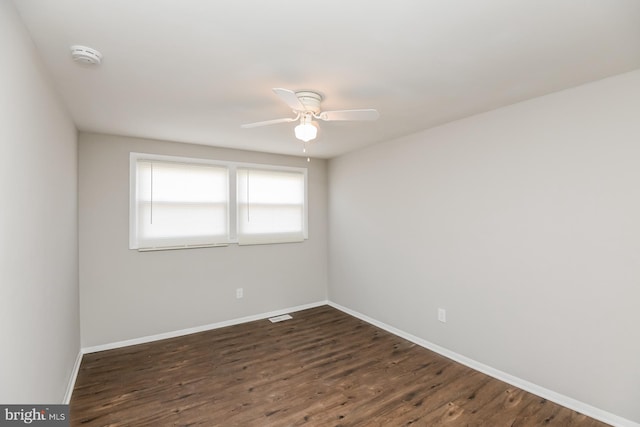 empty room with ceiling fan and dark hardwood / wood-style flooring