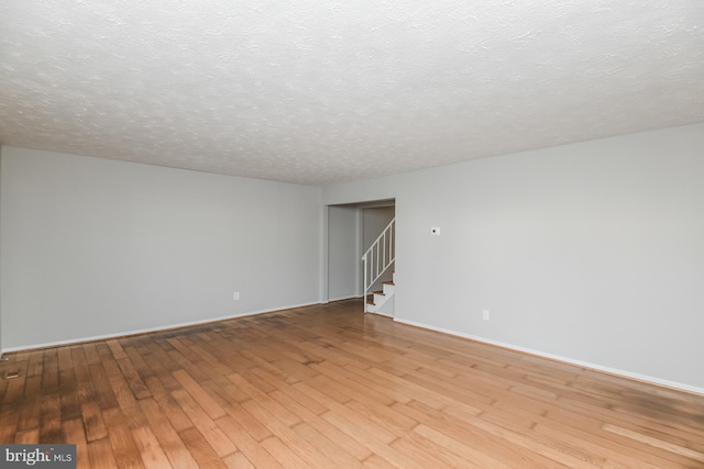 empty room with a textured ceiling and light wood-type flooring