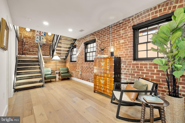 unfurnished room with plenty of natural light, brick wall, and hardwood / wood-style floors