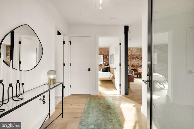 hall featuring brick wall and light wood-type flooring