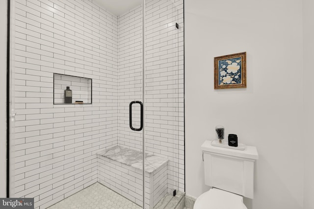 bathroom featuring a shower with shower door and toilet