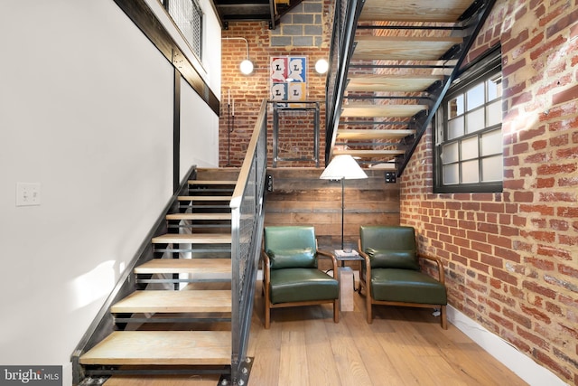 stairway featuring hardwood / wood-style flooring and brick wall