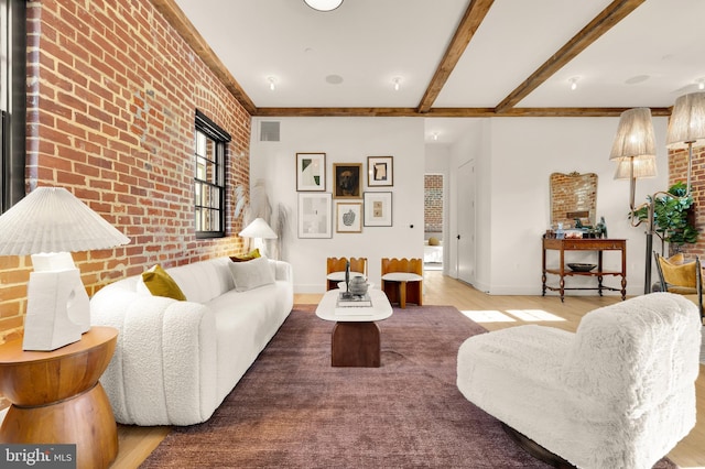 living room with light hardwood / wood-style flooring, beam ceiling, and brick wall