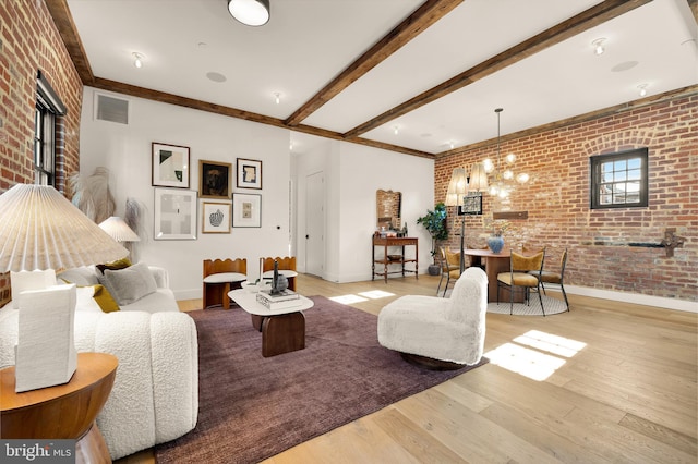 living room with light hardwood / wood-style floors, brick wall, and beamed ceiling