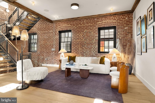 sitting room featuring brick wall, beam ceiling, and light hardwood / wood-style floors