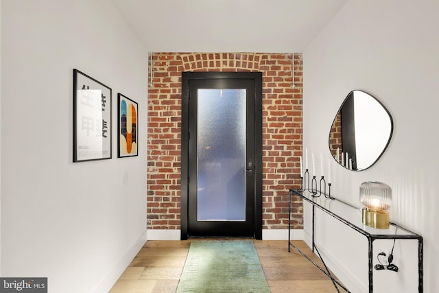 foyer with light hardwood / wood-style floors and brick wall