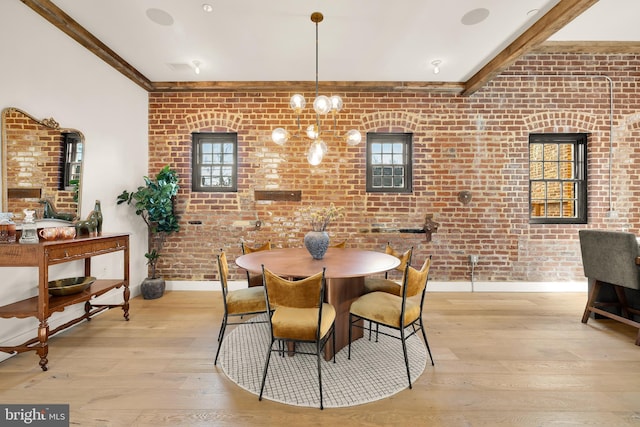 dining area with light hardwood / wood-style floors and brick wall