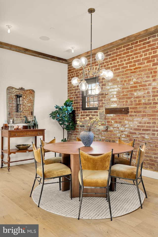 dining area featuring crown molding, light wood-type flooring, and brick wall