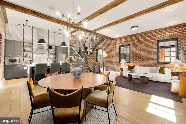 dining area featuring brick wall, light hardwood / wood-style flooring, and beam ceiling