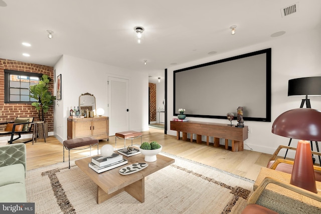 cinema with light wood-type flooring and brick wall