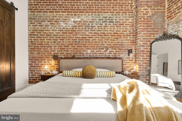 bedroom featuring brick wall and a barn door