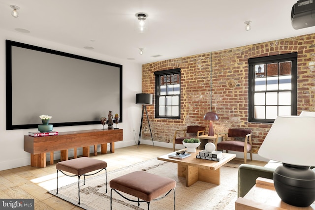 home theater featuring light hardwood / wood-style flooring and brick wall