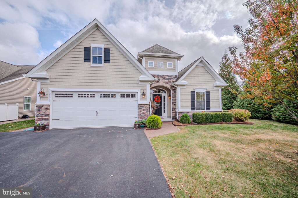 34901 Seagrass Plantation Ln, Dagsboro, DE 19939 - craftsman-style house featuring aphalt driveway, a garage, stone siding, and a front yard