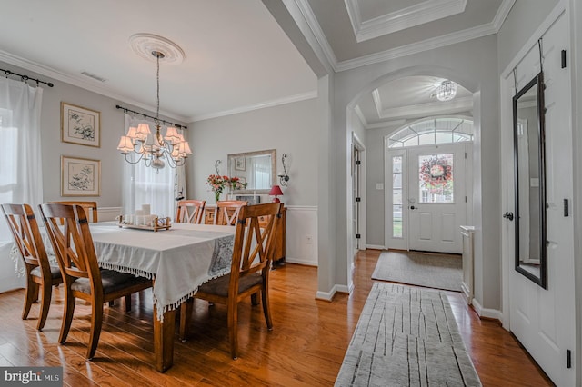 dining area featuring an inviting chandelier, ornamental molding, and light hardwood / wood-style flooring