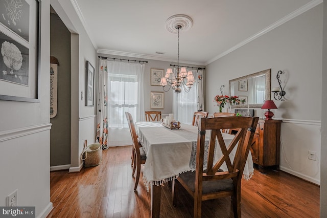 dining room with an inviting chandelier, hardwood / wood-style flooring, and crown molding