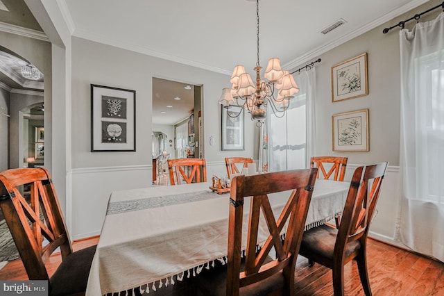 dining area with light hardwood / wood-style floors, an inviting chandelier, and crown molding