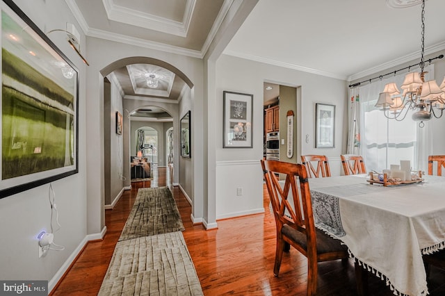 dining room with hardwood / wood-style floors, a notable chandelier, and crown molding