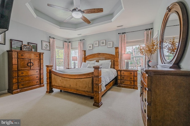 carpeted bedroom with a tray ceiling, multiple windows, and ceiling fan