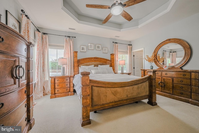 bedroom featuring ceiling fan, a raised ceiling, and light colored carpet