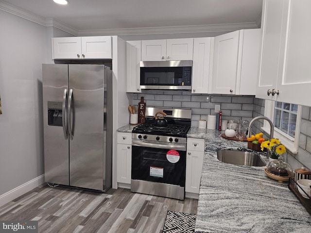 kitchen with stainless steel appliances, white cabinets, and light stone countertops