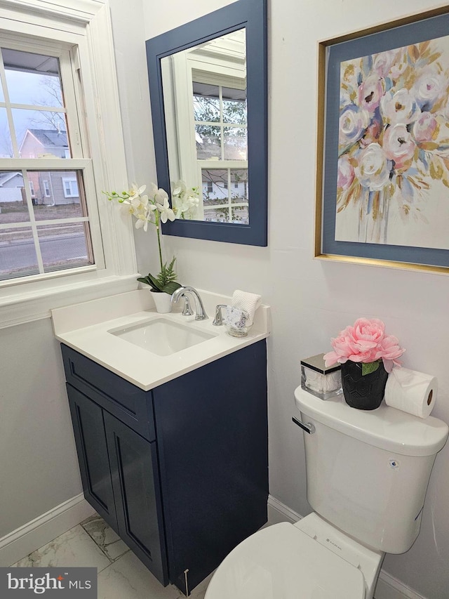 bathroom with toilet, a wealth of natural light, and vanity