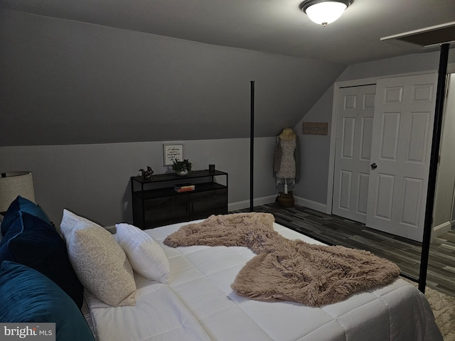 bedroom featuring dark hardwood / wood-style floors, a closet, and lofted ceiling