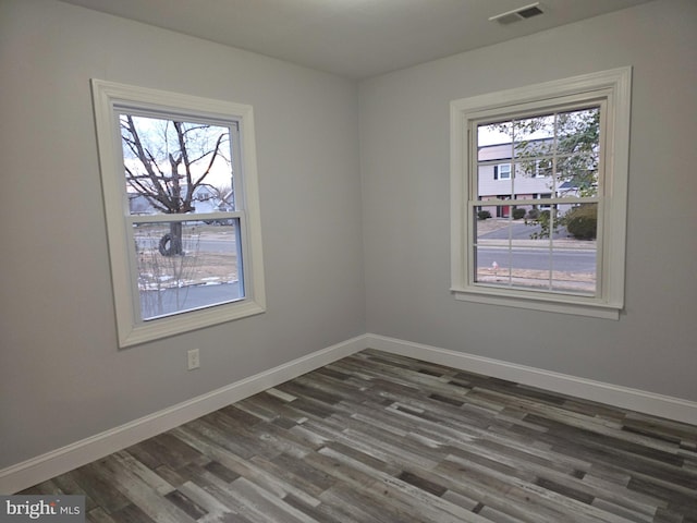 spare room with dark hardwood / wood-style flooring and plenty of natural light