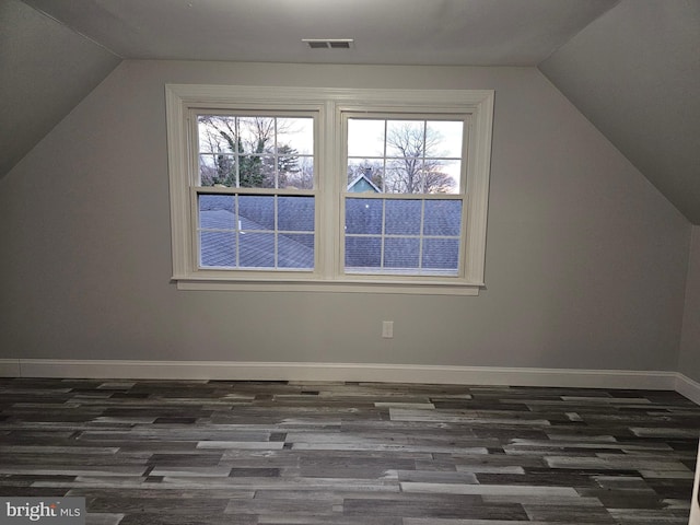 additional living space with vaulted ceiling and dark wood-type flooring