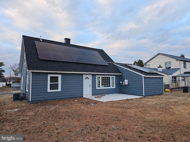 back of property with central air condition unit, solar panels, and a patio