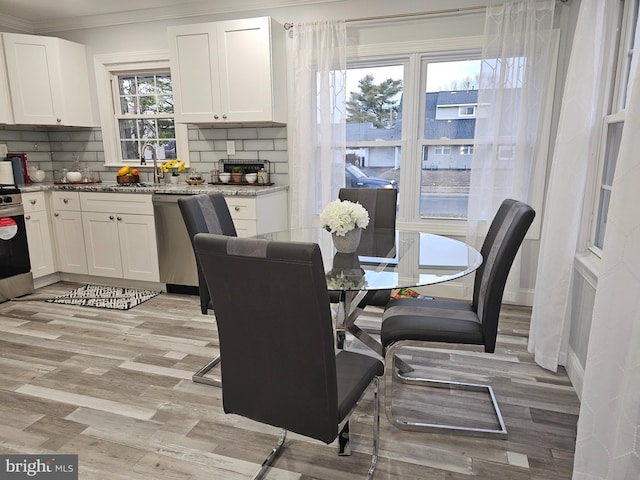 dining room with sink, a wealth of natural light, crown molding, and light wood-type flooring