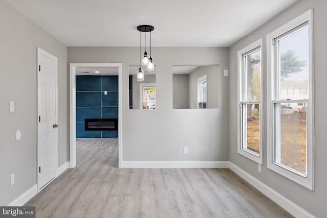 unfurnished dining area with a large fireplace and light wood-type flooring