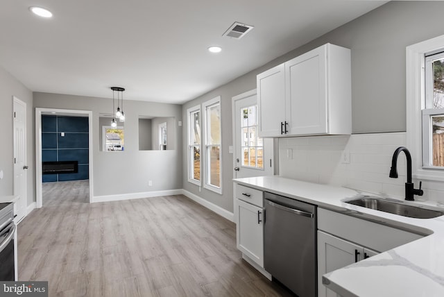 kitchen with a wealth of natural light, white cabinetry, dishwasher, and sink