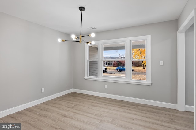 unfurnished dining area featuring light hardwood / wood-style floors and an inviting chandelier