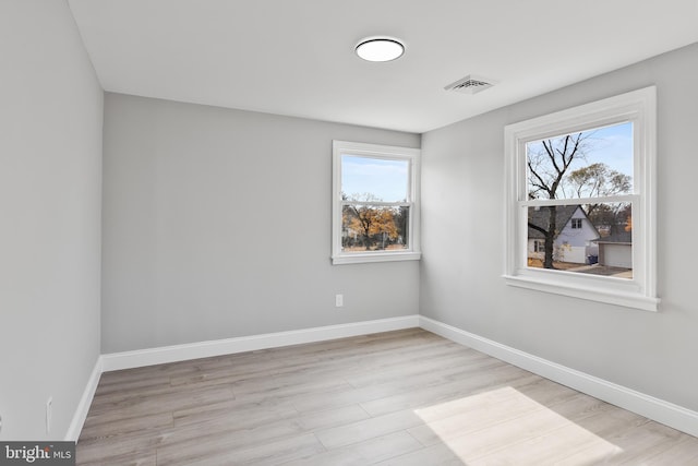 empty room with a wealth of natural light and light hardwood / wood-style floors