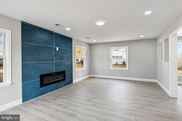 unfurnished living room featuring a large fireplace and light hardwood / wood-style flooring