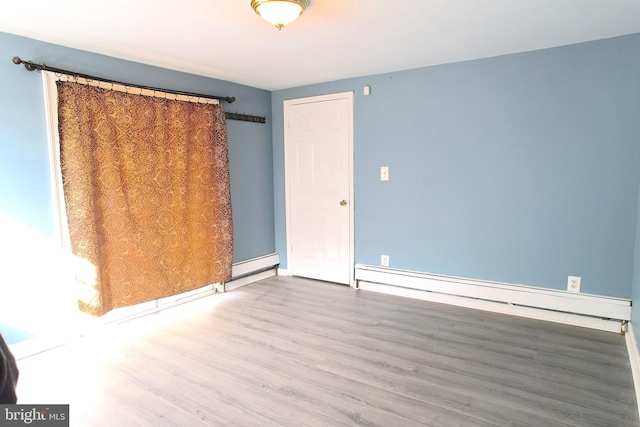 spare room with baseboard heating and hardwood / wood-style floors